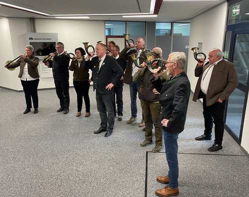 Zur Überraschung des Ehepaares Schmitt ertönten im Kreishaus Lüdenscheid Jagdsignale, vorgetragen von den Jagdhornbläsern der Märkischen Kreisjägerschaft. Foto: Alexander Bange / Märkischer Kreis 