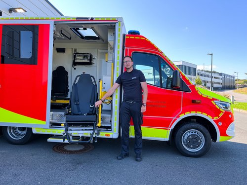 Florian Tremblau (stellvertretender Leiter Rettungswache Rosmart) zeigt den neuen elektrohydraulischen Tragestuhl vom Krankentransportwagen. Foto: Hannah Heyn / Märkischer Kreis