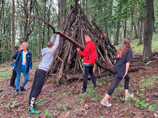 Zelt aus Baumstämmen im Wald bauen