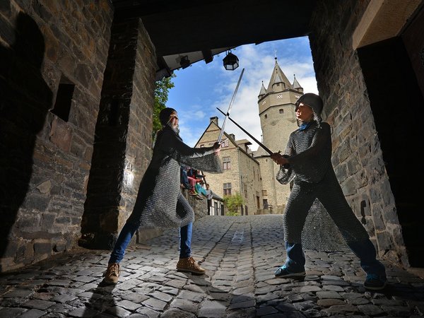 Kinder, die als Ritter verkleidet sind, kämpfen im Burgtor. Im Hintergrund ist der Obere Burghof.