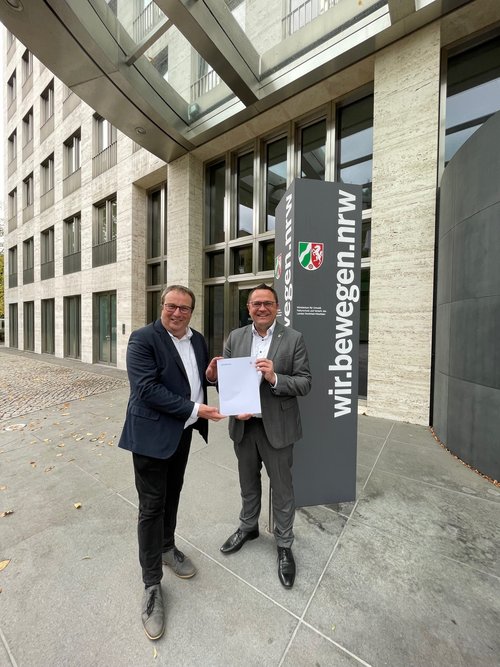 Der nordrhein-westfälische Verkehrsminister Oliver Krischer (links) hat dem Landrat des Märkischen Kreises, Marco Voge, einen Förderbescheid über 2,96 Millionen Euro für das ÖPNV-Angebot überreicht. Foto: Ministerium für Umwelt, Naturschutz und Verkehr des Landes Nordrhein-Westfalen 